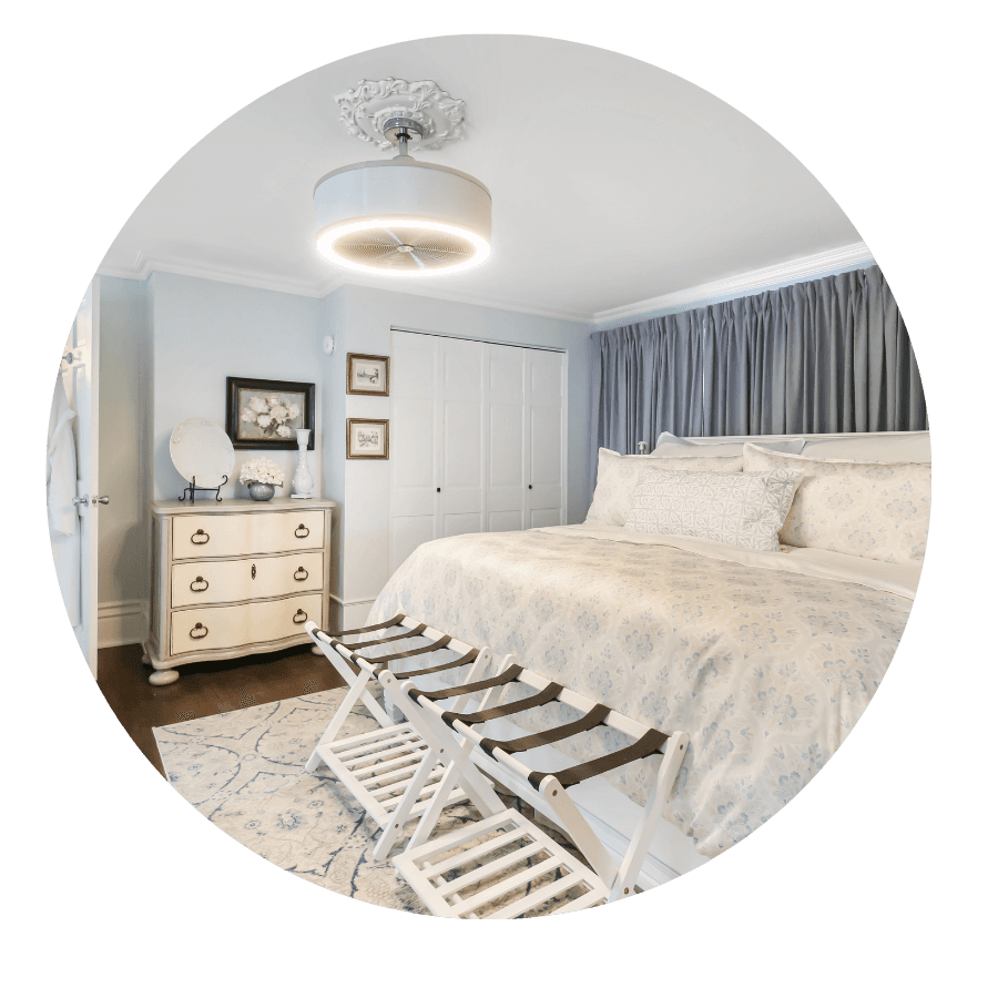 A beautifully styled bedroom featuring a light-colored bed, a decorative dresser, and elegant drapes.