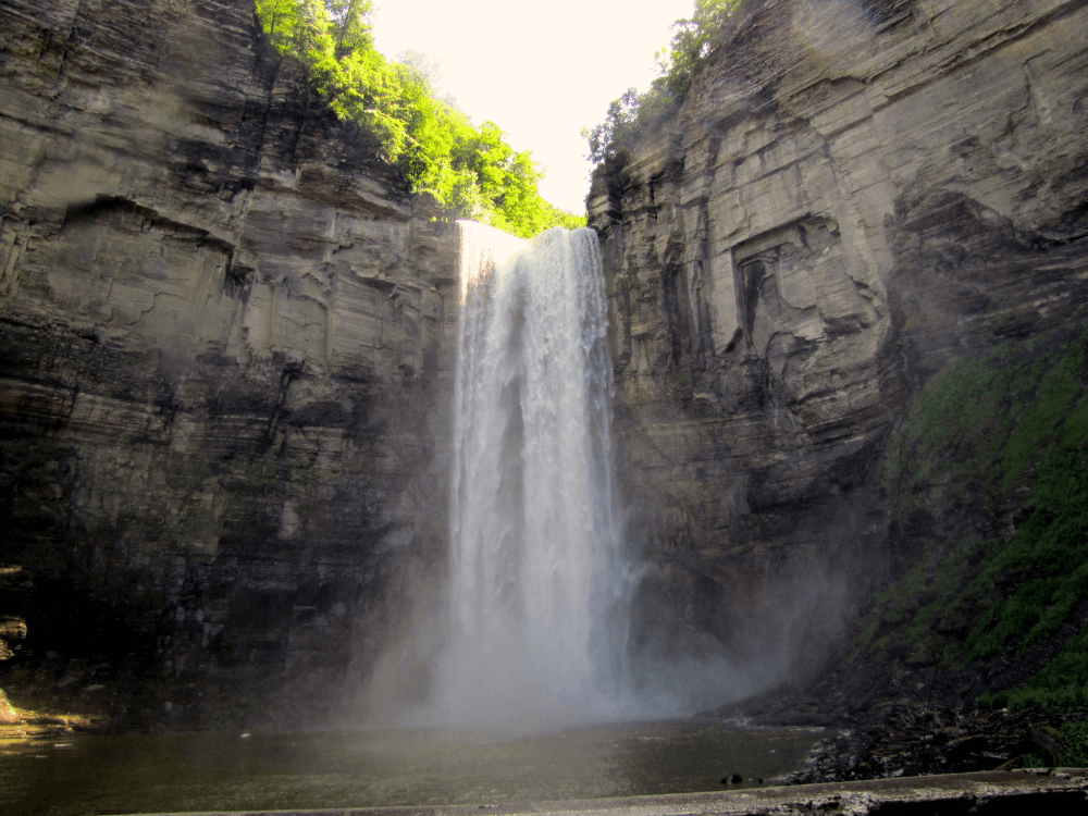 A majestic waterfall cascading down rocky cliffs surrounded by lush greenery.